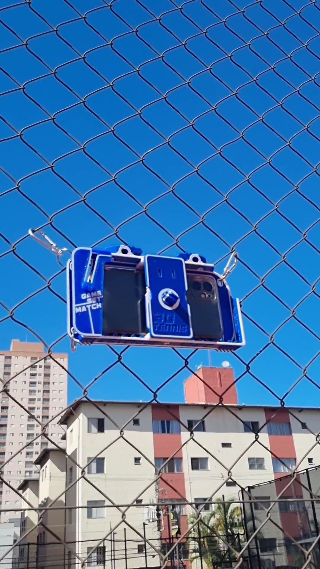 Celular instalado no suporte do alambrado da quadra